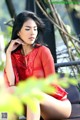 A woman in a red dress sitting on a bench.