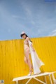 A woman in a white bikini standing on a white bench.