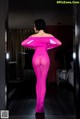 A woman in a pink bodysuit standing in a room.