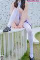 A woman sitting on top of a white bench.