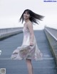 A woman in a white dress standing on a bridge.